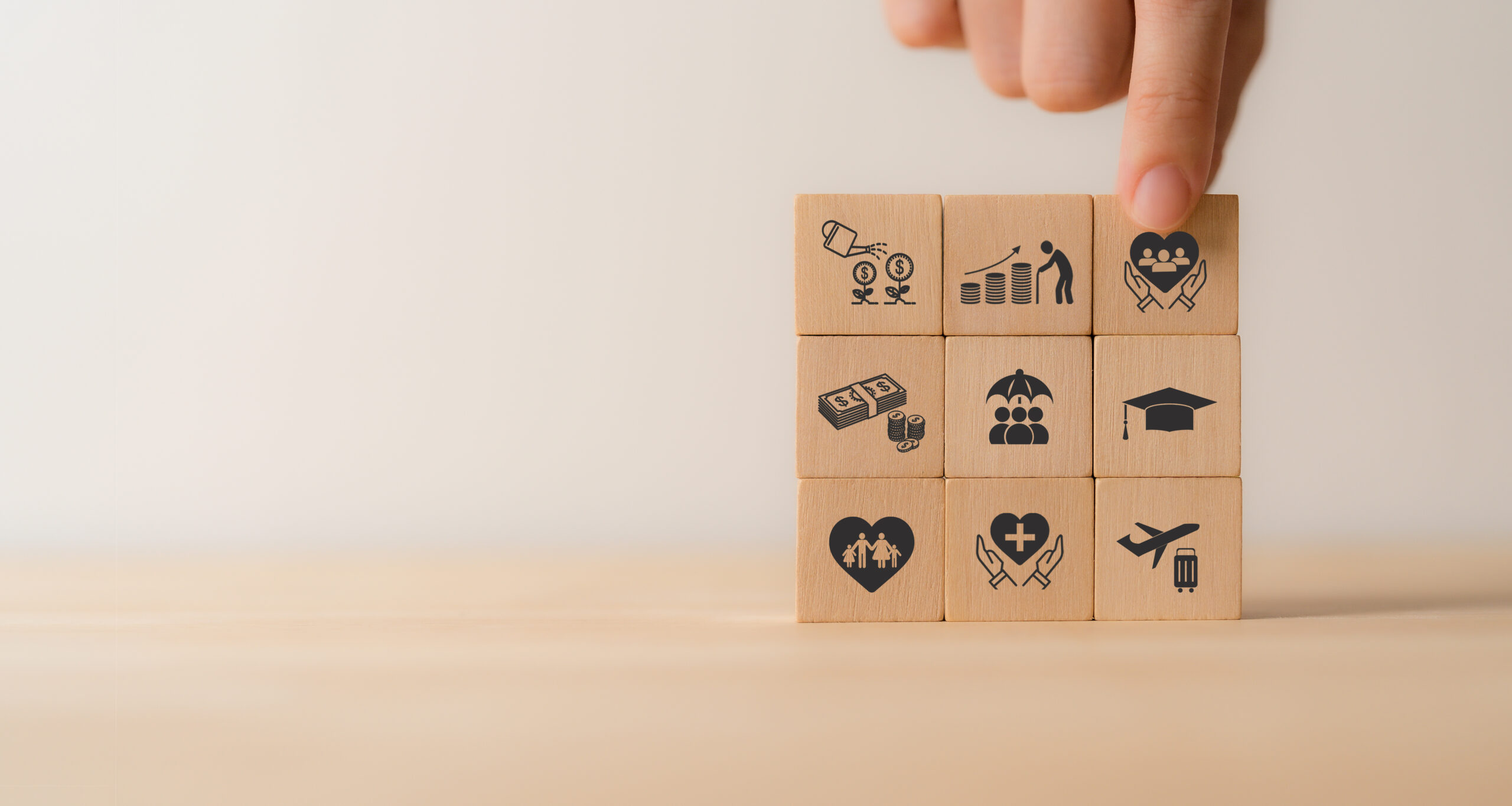 Holzkl&ouml;tze mit Symbolen f&uuml;r Bildung, Gesundheit, Arbeit und Gemeinschaft, angeordnet in einem 3x3-Raster.